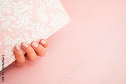 Beautiful young woman's hand on pink background.