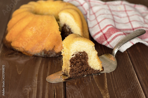 Group of one whole one slice of fresh baked marble gugelhupf sweet bread variety with a tea towel on brown wood photo