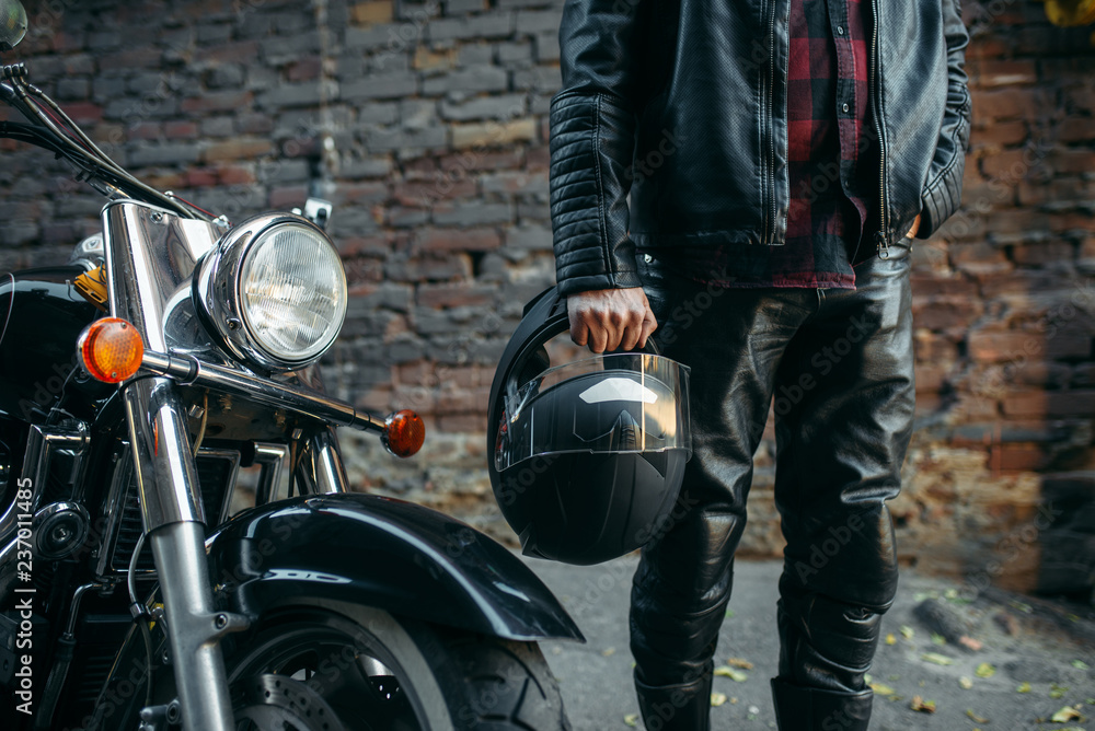 Fototapeta premium Biker in leather jacket with helmet in hand