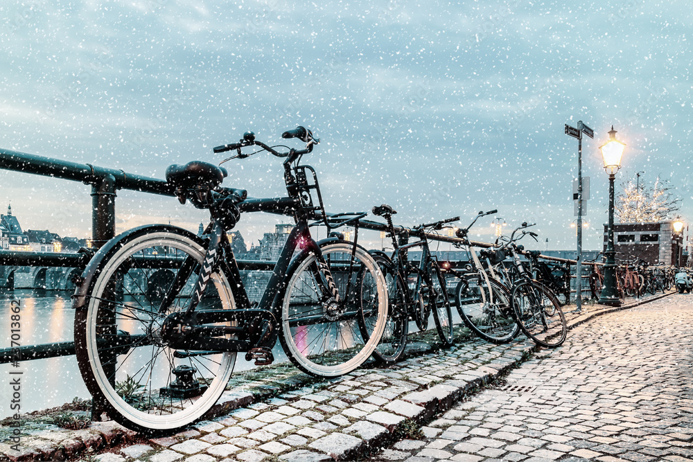 Fototapeta premium Winter view of parked bicycles alongside the Dutch river Maas