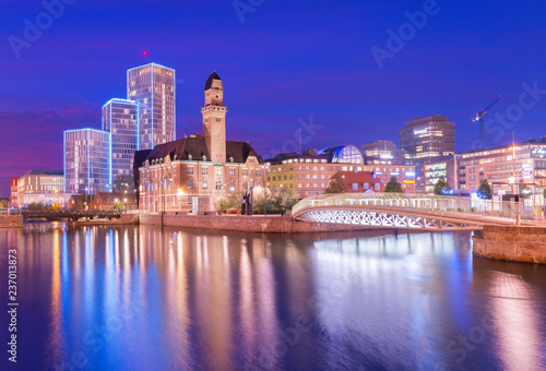 Obraz na płótnie A view of a city at night. An evening panorama of Malmo is reflected on the water, Sweden. Long exposure photo with smooth nice reflections w salonie