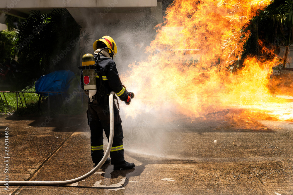 Firefighters with extinguisher spraying high pressure water to fighting the fire flame in an emergency situation. Firefighters with extinguisher spraying high pressure water to fighting the fire flame in an emergency situation.