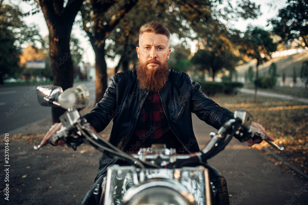 Bearded motorcyclist sitting on classical chopper