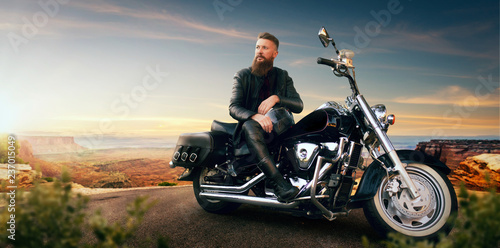 Biker sitting on his chopper and looks on sunset