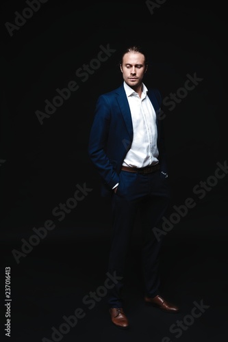 Full length of elegant young handsome man posing in fashionable suit, looking at camera. Studio shot