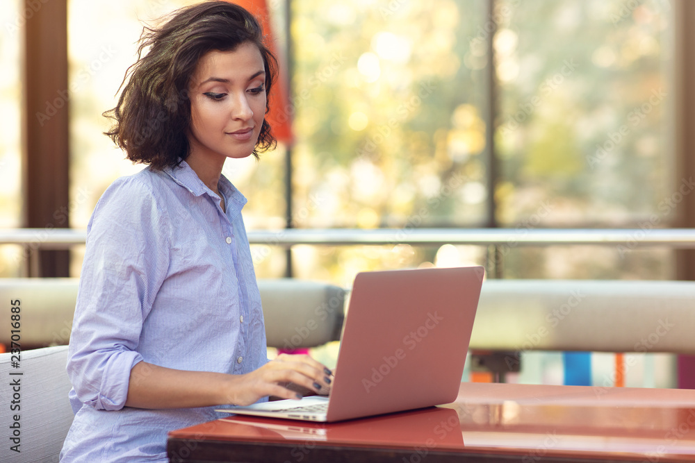 Image of happy woman using laptop while sitting at cafe. Image of happy woman using laptop while sitting at cafe.