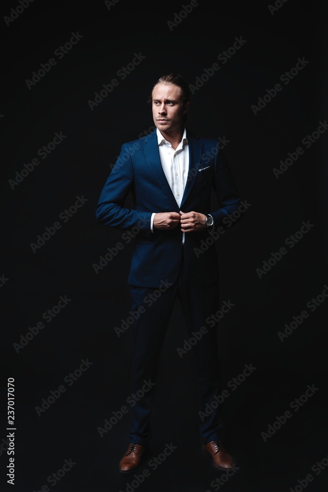 Full length of elegant young handsome man posing in fashionable suit, looking at camera. Studio shot Full length of elegant young handsome man posing in fashionable suit, looking at camera. Studio shot