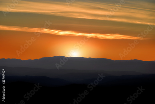 Fototapeta Naklejka Na Ścianę i Meble -  A beautiful sunset behind the silhouette of a mountain