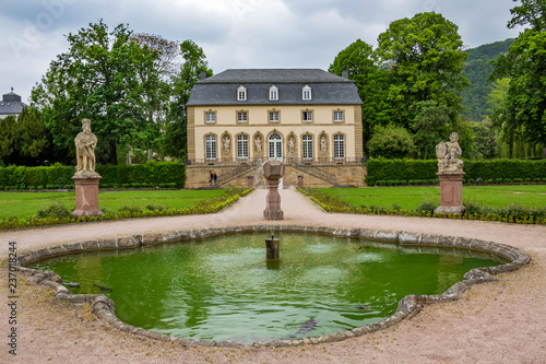 The abbey garden in Echternach - the oldest town in Luxembourg, with a fountain and the building of the Orangery on an overcast May day photo