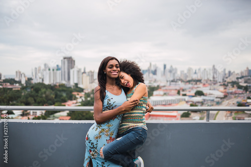 Embracing happy black women on terrace