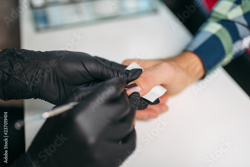 Master in gloves polishing nails to male client