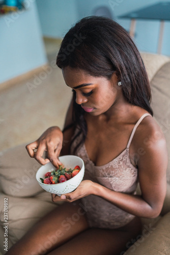 Sensual black woman having strawberries at home