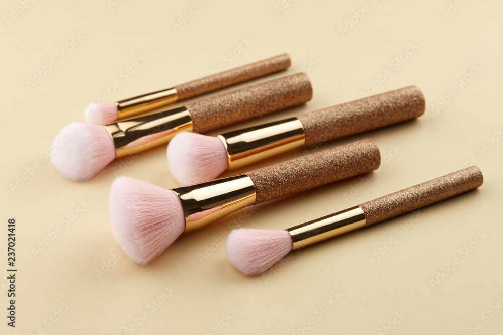 Make up brushes in a row close up on beige background Make up brushes in a row close up on beige background