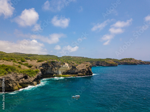 Manta bay on Nusa Penida island. Aerial drone view on coast, blue ocean, boat and manta rays.