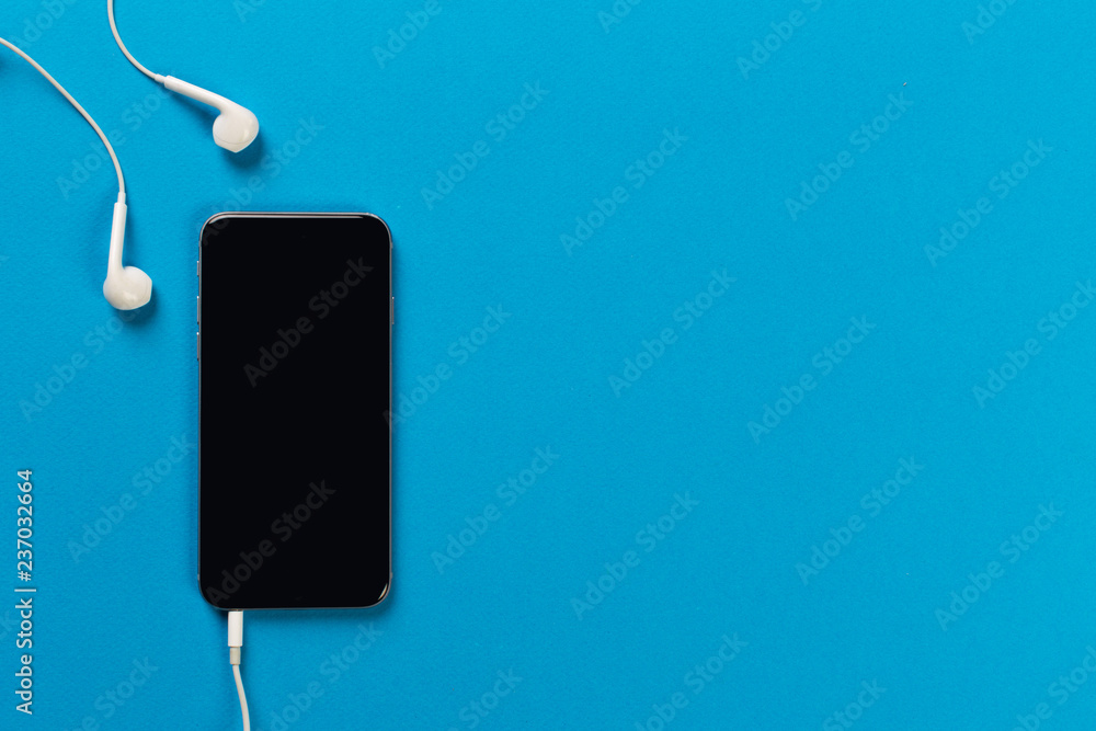 Mobile phone with white earphones on colour backgroung, top view Mobile phone with white earphones on colour backgroung, top view
