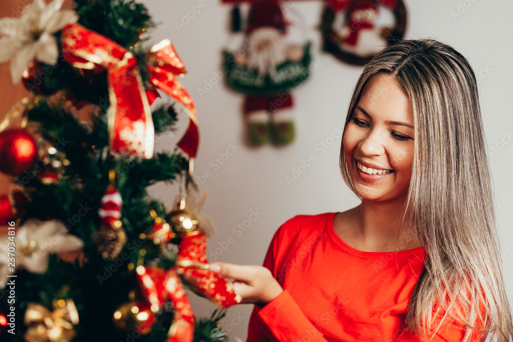 Happy woman Decorating Christmas Tree in their Home. Smiling Woman Celebrating Christmas or New Year. Christmas Tree Decoration.