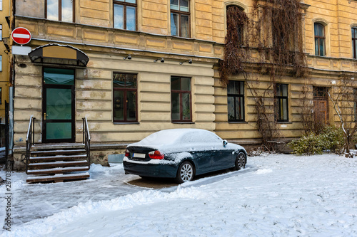 At the multi-storey yellow house on the roadside parked snow-covered car. © ako-photography