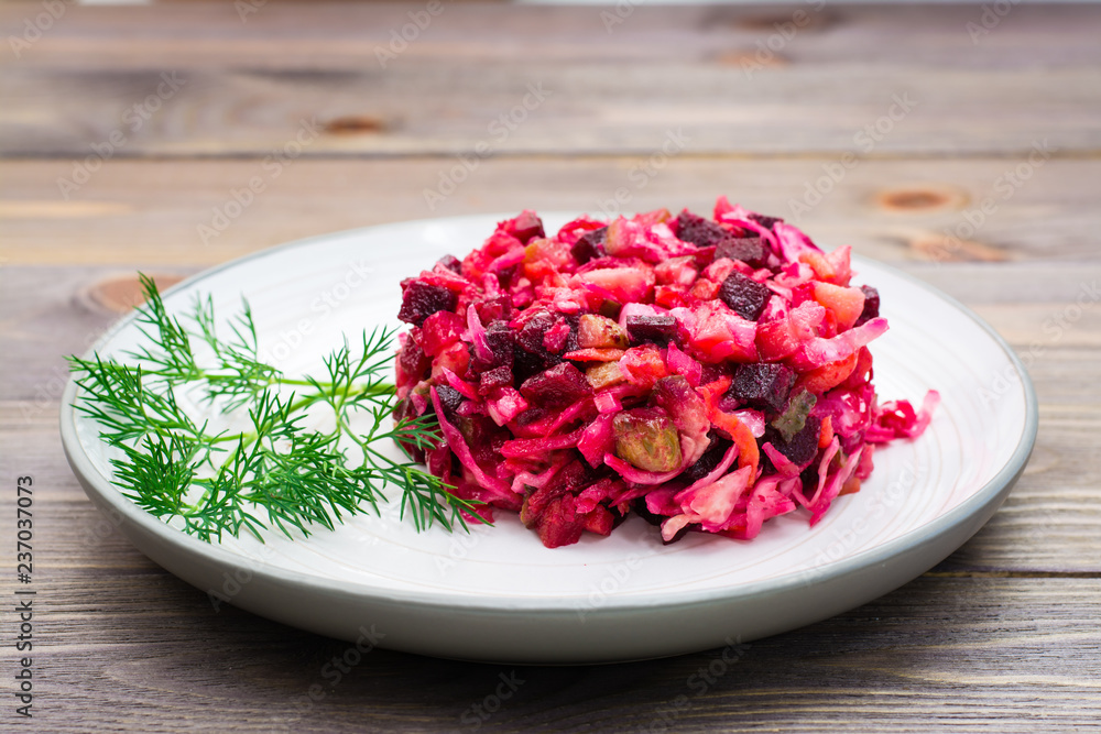 National Russian salad - vinaigrette - from boiled vegetables, sauerkraut and pickled cucumbers on a plate on a wooden table National Russian salad - vinaigrette - from boiled vegetables, sauerkraut and pickled cucumbers on a plate on a wooden table