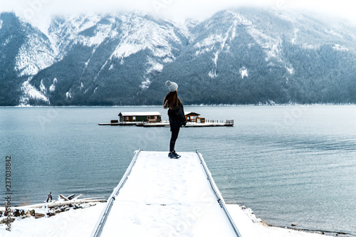 Girl on pier overlooking Lake Minnewanka and snowy mountains in Banff National Park photo