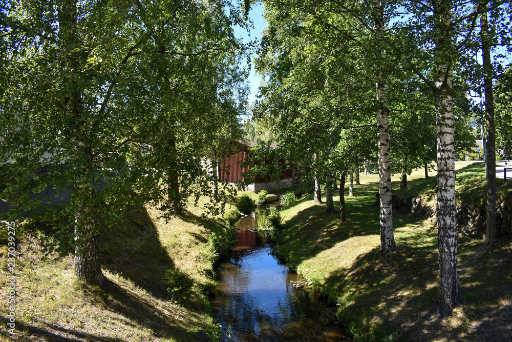 Clean canal surrounded by grass and trees.