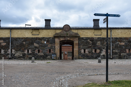 A long cobblestone wall with an entrance to another architectural building in Suomenlinna Sea Fortress in Finland.