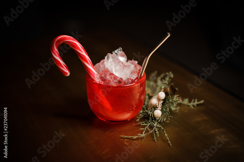 Delicious christmas cocktal in red cup decorared with candy near the fir-tree branch photo