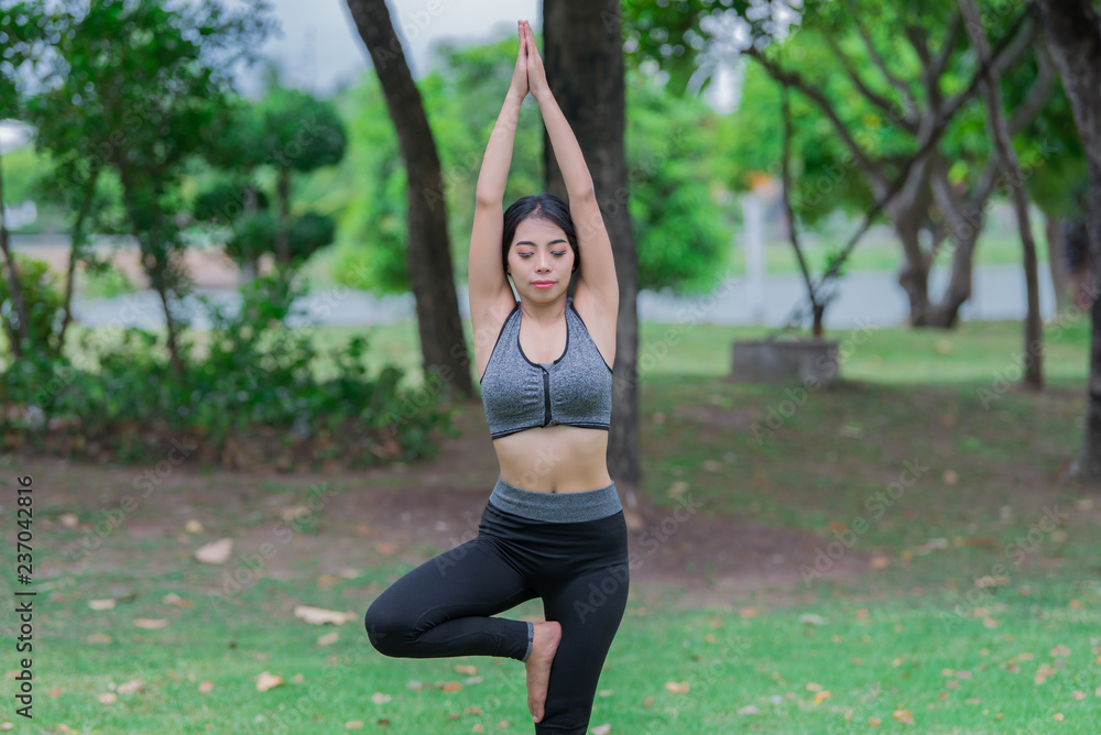Slim girl play yoga on the lawn at the park,relax in nuture,Asian Girls love health practicing yoga
