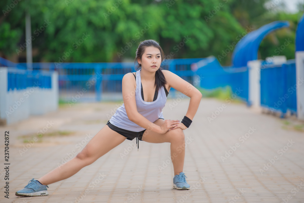 Asian sporty woman stretching body breathing fresh air in the park,Thailand people,Fitness and  exercise concept,Jogging in the track,Fat girls want to thin.