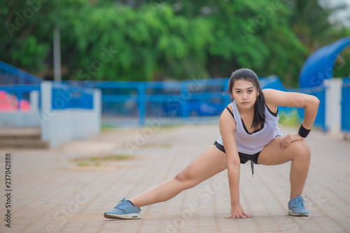 Asian sporty woman stretching body breathing fresh air in the park,Thailand people,Fitness and exercise concept,Jogging in the track,Fat girls want to thin.