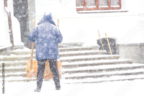 One women shovelling snow in the snowstrom. Cleaning stairway photo