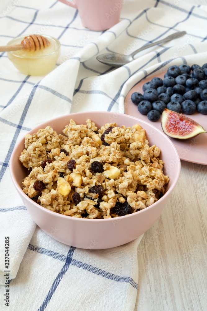Pink bowl of fruit granola with fruits and honey, side view. Close-up. Pink bowl of fruit granola with fruits and honey, side view. Close-up.