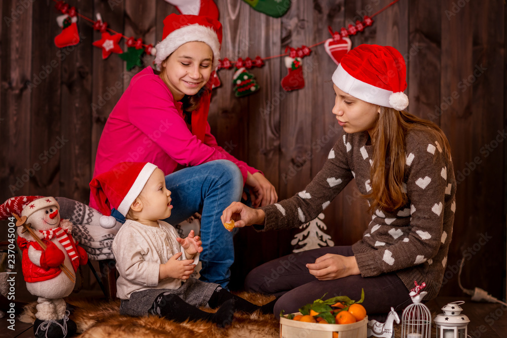 Children, sisters and baby play in a dark Christmas interior.