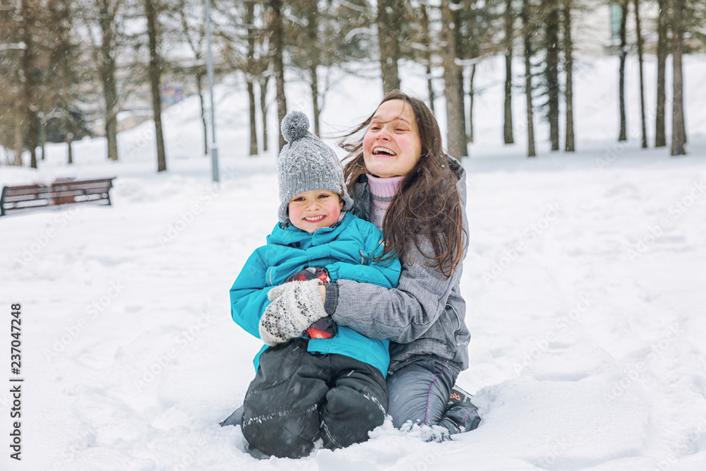 Young woman with her little son playing in the snow in winter