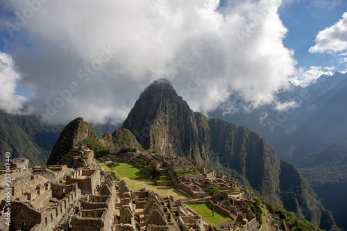 Machu Picchu in Peru - lost city of Incan Empire is UNESCO heritage. Sunny summer day with blue sky and clouds