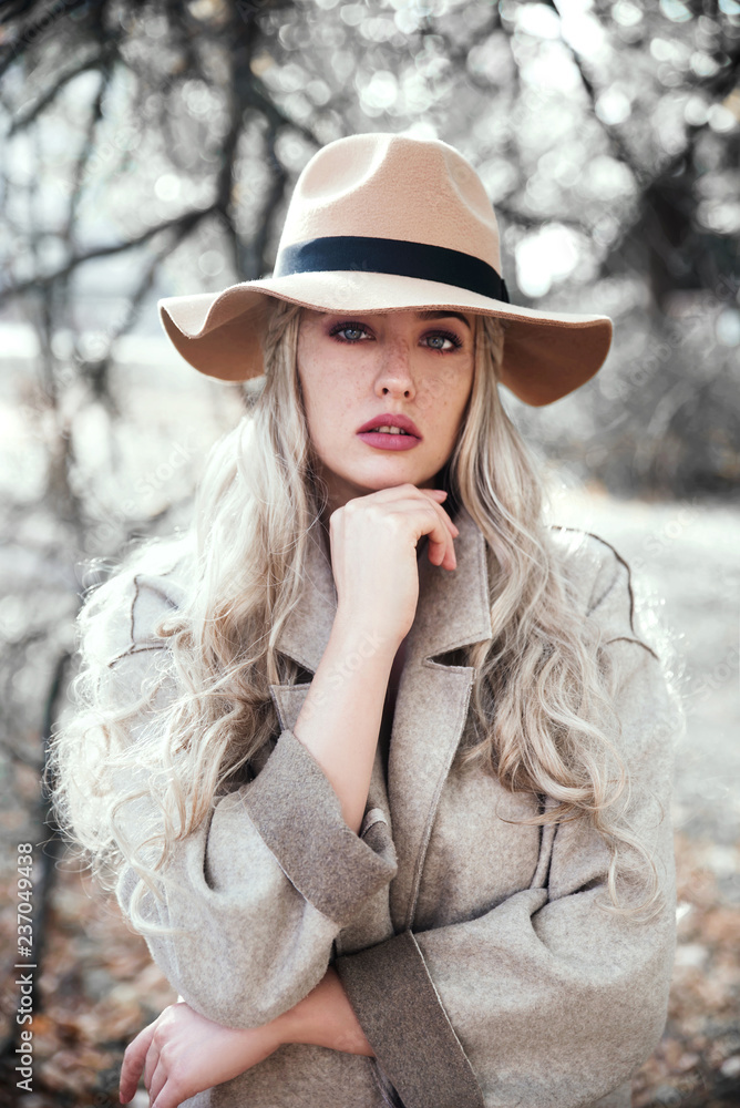 Young blonde woman wearing coat and hat in nature