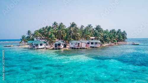 Aerial drone view of Tobacco Caye small Caribbean island with palm trees and bungalows in the Belize Barrier Reef photo