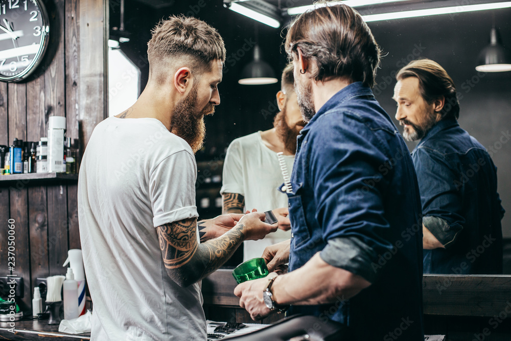 Curious man standing next to professional barber and looking at blades Curious man standing next to professional barber and looking at blades