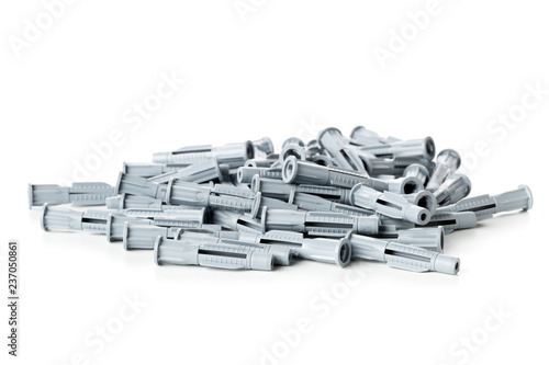 Heap of unused, new, grey plastic wall plug bolts over white