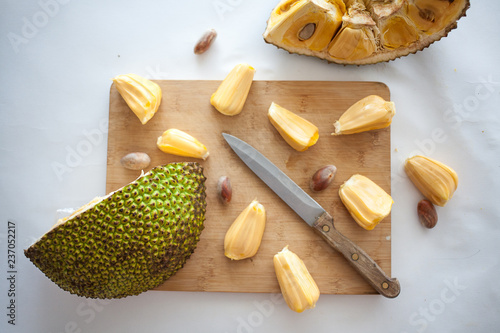 Photos Ripe Jackfruit pieces with jackfruit pods on wooden desk with knife isolated on