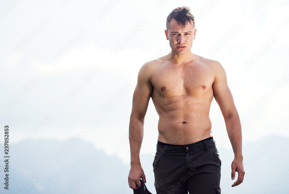 Handsome shirtless muscular male standing outdoors