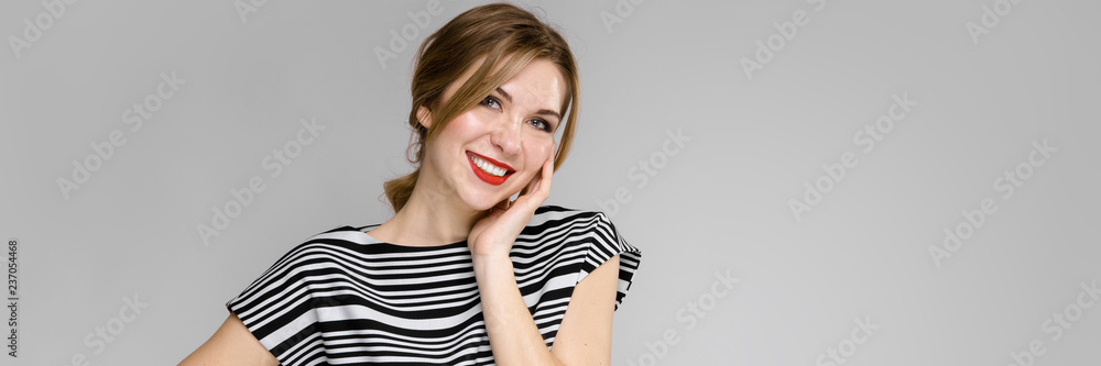 Portrait of a smilling girl on a gray backgroud. Girl holding her face Portrait of a smilling girl on a gray backgroud. Girl holding her face