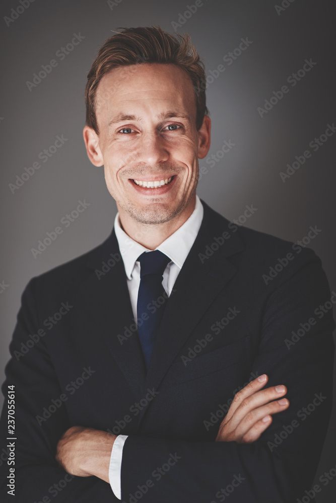 Young businessman smiling confidently while standing against a g Young businessman smiling confidently while standing against a g