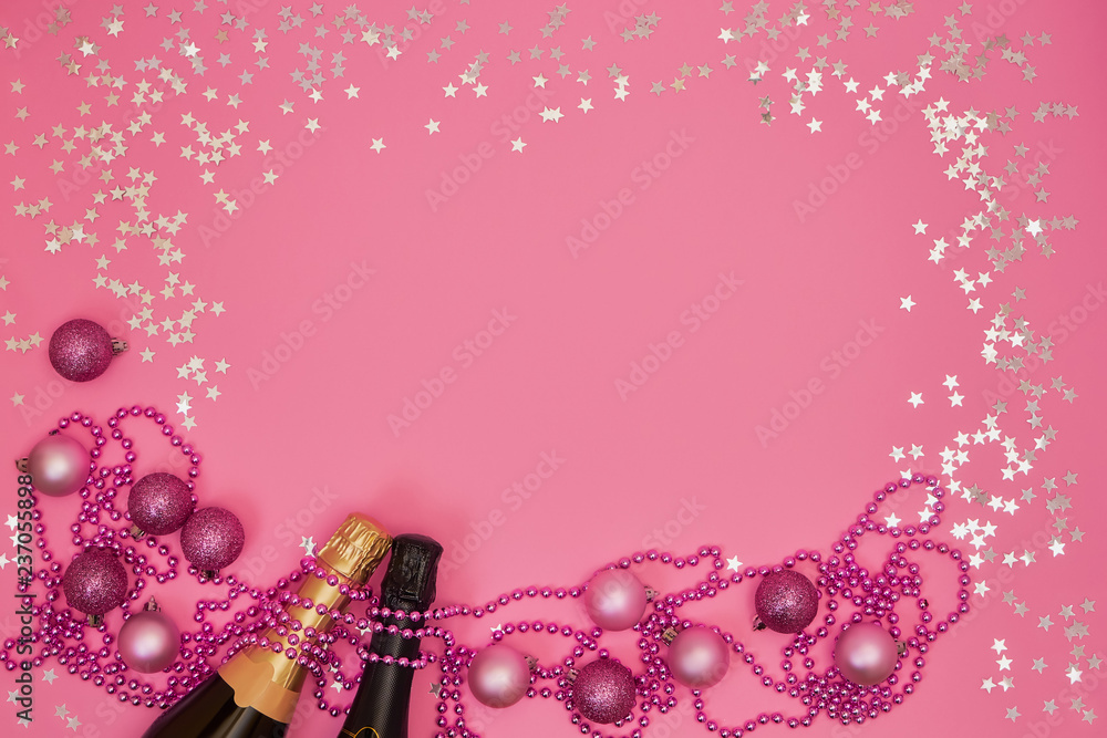 Two Champagne bottle with Christmas ornaments on pink background. Copy space, top view, flat lay