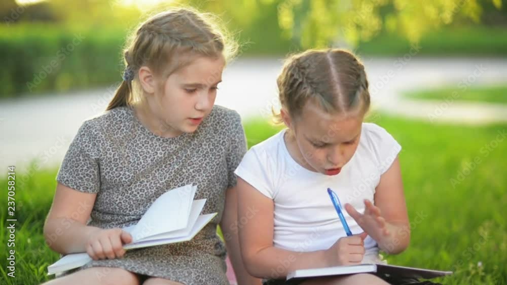 Kids Reading a Book in Summer Garden. Preschool Friends playing and Learning. Girls Doing Their Homework. Kids Reading a Book in Summer Garden. Preschool Friends playing and Learning. Girls Doing Their Homework.