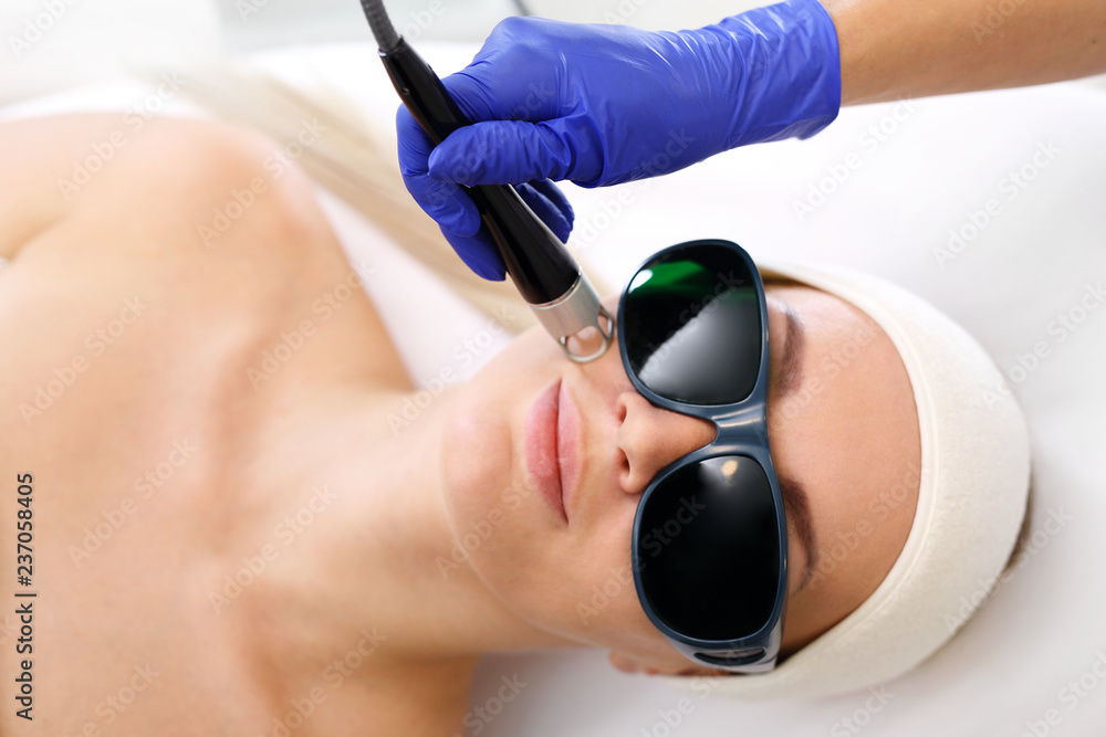 Obraz premium Fotoodmładzanie za pomocą lasera. Kobieta w salonie kosmetycznym podczas zabiegu z użyciem lasera.