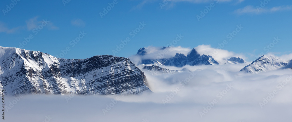 Snowy sunlight mountains in haze and blue sky at nice sun day