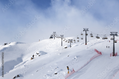 Snowy ski slope and ski-lift at ski resort at sunny winter evening