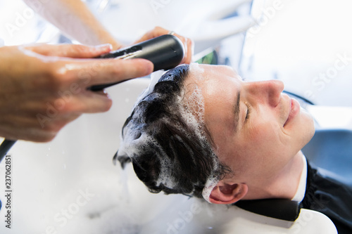 Profile view of a young man getting his hair washed and his head massaged in a hair salon