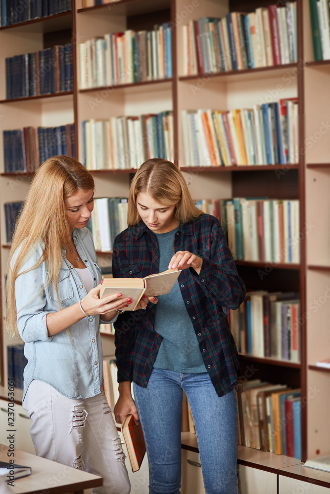 Couple of young female designers come to public library for new ideas, looking through the old magazines and annuals for inspiration. Couple of young female designers come to public library for new ideas, looking through the old magazines and annuals for inspiration.