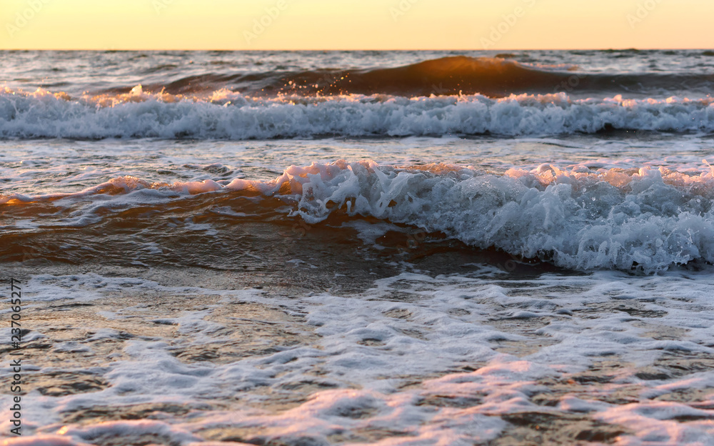 Obraz premium Sunset over the sea. Reflection of sunlight in the sea waves. Red and yellow sky in the rays of the sunset.